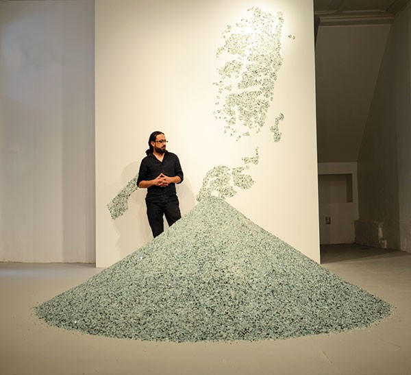 Bashar Alhroub with his work "Diamond Land," made of broken glass. The map on the wall depicts Palestine.