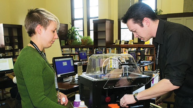 Hannah Schilperoort and Wes Roberts of the Carnegie Library use the facility's 3-D printer