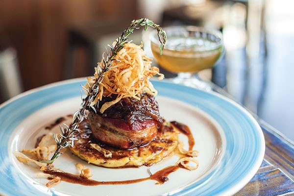 Bacon-wrapped bison meatloaf atop potato-cauliflower pancake, with fried onions, onion jam and balsamic onion jus