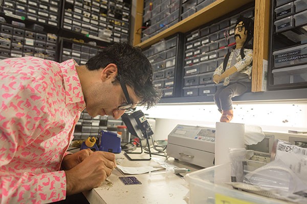 Ali Momeni solders a circuit-board at his lab at Carnegie Mellon University.