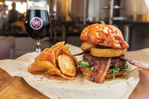 Beer-cheese-filled burger, with black-pepper bacon, garlic aioli, jerk pickles, arugula and ale-battered onion ring, and side of potato chips