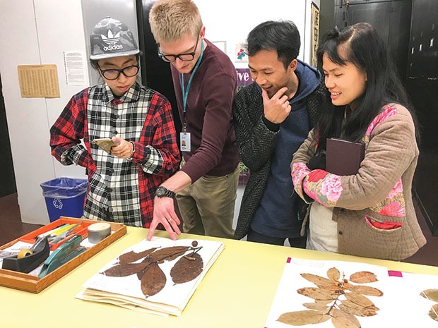 Members of the Art Labor collective study coffee herbarium specimens at Carnegie Museum of National History with Mason Heberling, postdoctoral research fellow