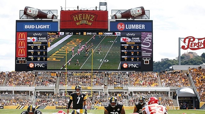 Two football teams, one wearing black and gold uniforms and the other wearing red and white uniforms, get into position at the former Heinz Field in Pittsburgh.