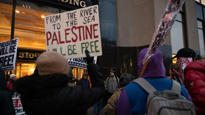 Protestors hold signs supporting Palestine on a cold, rainy day.