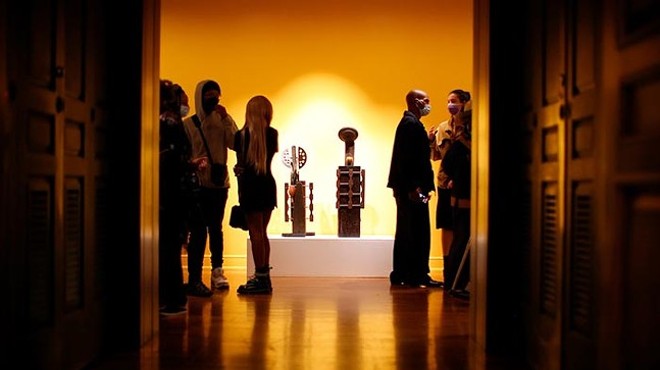 A group of people looks at art in a softly lit room.