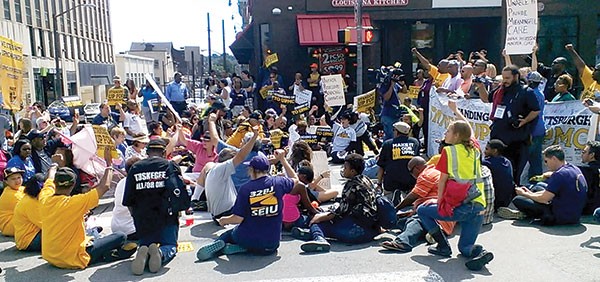 Protesters briefly sat down in the middle of Fifth Avenue and Atwood Street to protest UPMC labor policies.