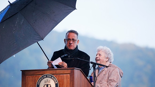 Actor Tom Hanks and Joanne Rogers stand at a podium under an umbrella during a rally in Downtown Pittsburgh.