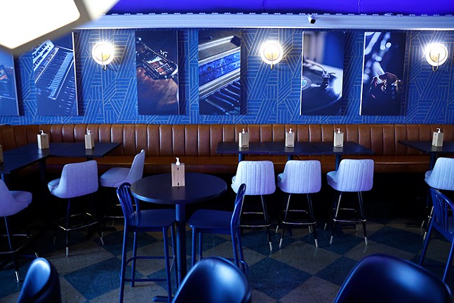 A blue room with tables and chairs and posters of music equipment