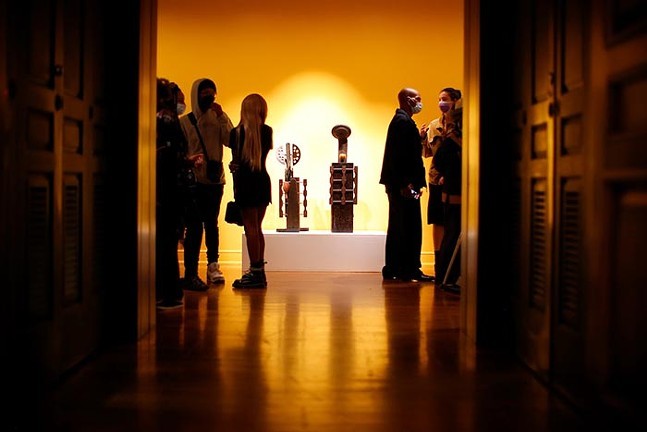 A group of people looks at art in a softly lit room.