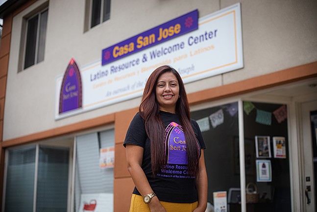 A woman stands in front of a building with a sign reading "Casa San Jose"
