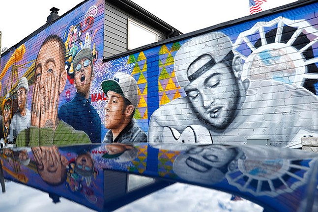 A large mural on the side of a building with multiple paintings of late Pittsburgh musician Mac Miller