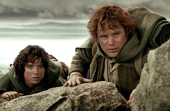 Two hobbits crawling on a rock
