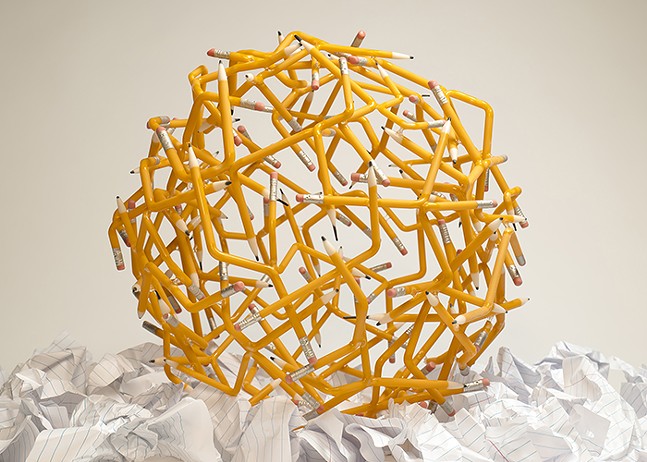 A sphere made up of pencil-shaped and -colored pieces of glass, on top of crumpled up pieces of notebook paper