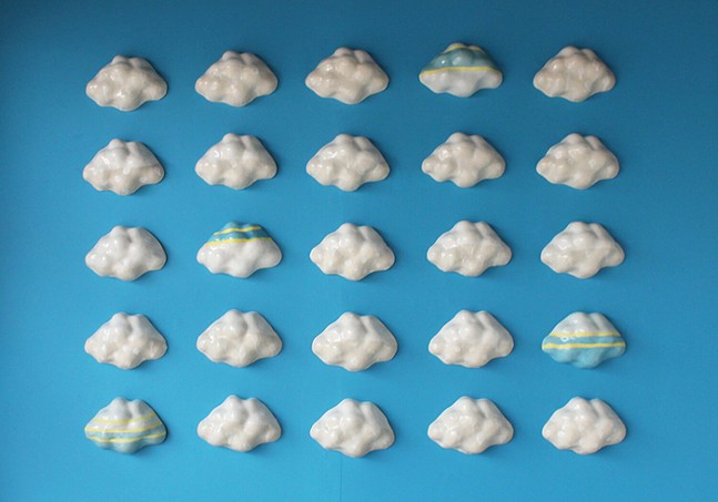 Ceramic clouds placed in a grid installed on a wall painted blue