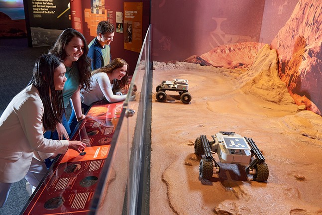 A group of young students interacts with a display at Mars: The Next Giant Leap.