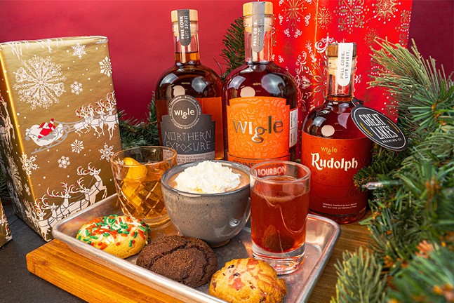 A colorful display of cocktails, cookies, and whiskey bottles surrounded by festive holiday decor.