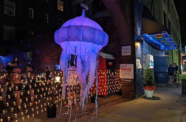 A giant inflatable jellyfish hangs outside of a festively lit bar.