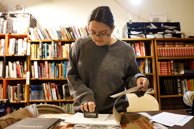 A woman stamps a page inside a book in a library