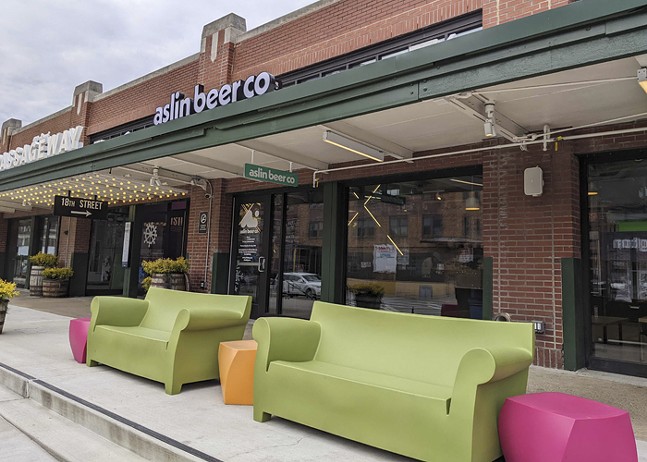 Neon-colored green, pink, and orange furniture sit outside a brewery.