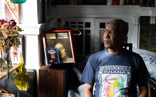 Carl Redwood wears a Ghana shirt in a room full of books and flowers