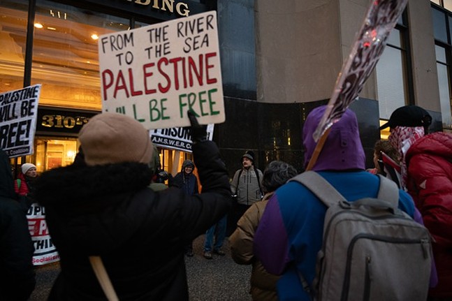 Protestors hold signs supporting Palestine on a cold, rainy day.