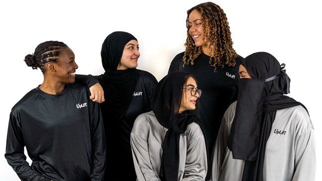 Femme athletes, some with curly and braided hair and others wearing the hijab, smile at one another