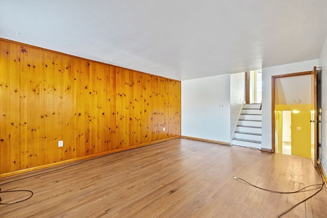 A spacious knotty-pine wall with a split-level staircase and polished wood floor.