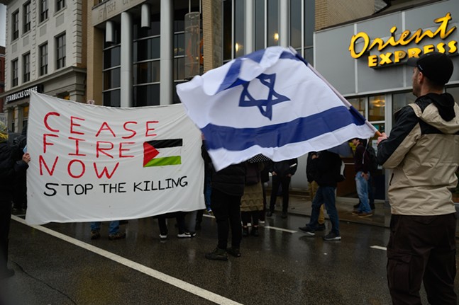 Protestors face off with pro-Palestine signs and an Israel flag.