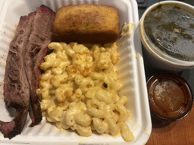 Several sections of tender brisket piled next to cornbread and mac and cheese