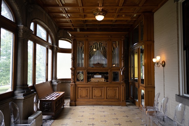 A large organ-like machine stands at the end of a room paneled in dark wood