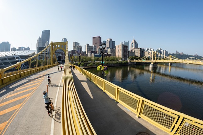 Cyclists ride across a car-free Roberto Clemente Bridge with the Pittsburgh skyline in background