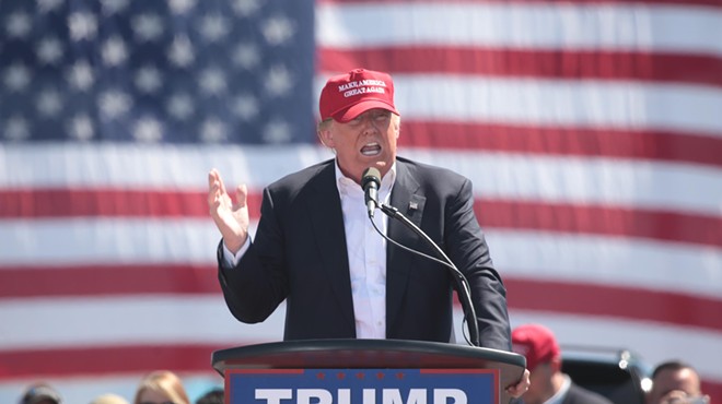 Donald Trump speaks at a podium with an American flag in the background